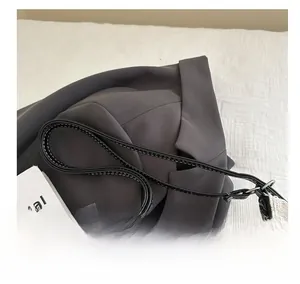 Detail of black leather handle with white stitching on a canvas tote bag on gray blazer