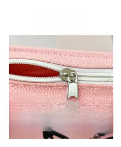 Macro view of a pink canvas tote bag showing the metal zipper closure and fabric texture