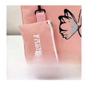 Detail of pink canvas tote bag featuring a detachable matching mini zipper pouch accessory