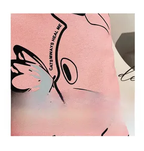 Detail of pink canvas tote bag fabric with cat and butterfly illustration and text
