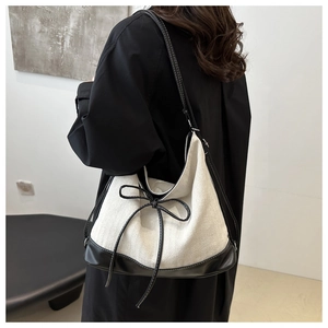 Detail of minimalist tote bag with cream fabric and black leather bow contrast finish