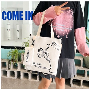 Detail of off-white canvas tote bag with cat illustration and matching small pouch