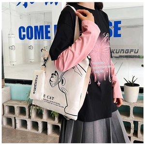 Detail of white canvas tote bag with cat print and small fashion coin purse attachment