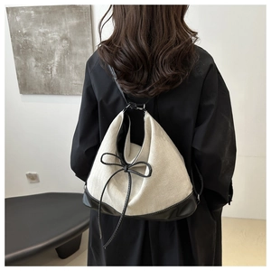 Detail of minimalist canvas and leather backpack worn by model in black trench coat