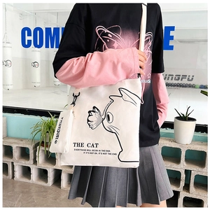 Detailed view of white canvas tote bag with cat illustration and small side zipper pouch
