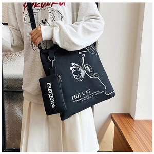 Detail of black canvas tote bag with white cat print and matching zipper pouch charm