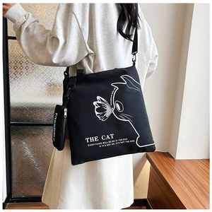 Detail of black canvas tote bag with cat illustration and mini fashion pouch accessory