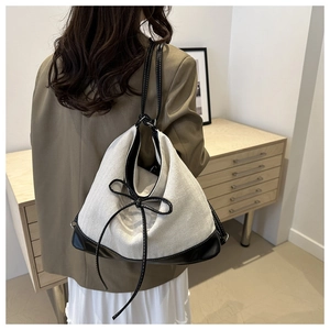 Detail shot of a large canvas tote bag with contrast black ribbon and leather trim handles