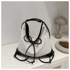 Detail of canvas tote bag with black leather trim and decorative bow in casual setting