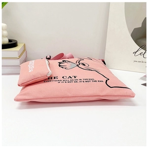 Detail of pink canvas tote bag featuring cat illustration and matching small zipper pouch