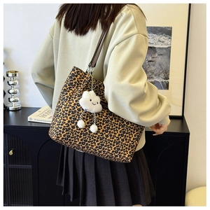 Detail of leopard print tote bag with brown leather straps and cloud charm accessory