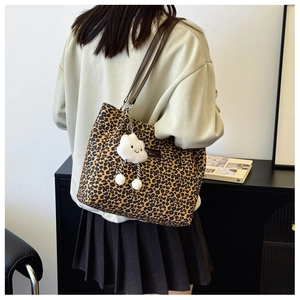 Detail of leopard print canvas tote bag featuring brown straps and a plush cloud charm