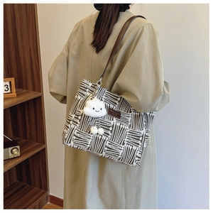 Detail of canvas tote bag with brown vertical stripes and a white cloud plush charm