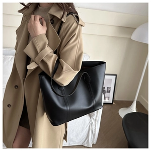 Side view of a black large capacity tote bag worn over the shoulder for daily commuting