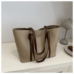 Minimalist beige tote bag with brown handles on a desk with a vintage lamp