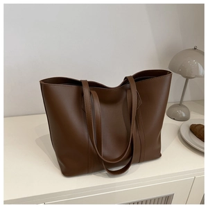Detail view of deep brown tote bag with vertical stitching and slim straps in minimalist setting