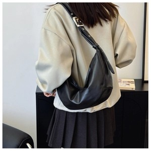 Detail of black leather crescent bag with adjustable silver hardware and knotted shoulder strap