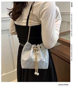 Detail of light blue wrinkled satin bucket bag with pearl tassels and gold chain strap