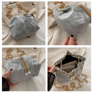 Detail view of marble pattern bucket bag with gold chain strap and pearl charms
