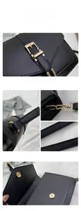 Close-up of black leather crossbody bag showing gold hardware and precise stitching detail