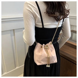 Detail view of pink bucket bag with pearl drawstring and golden chain strap on model