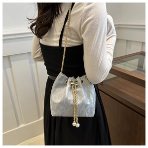Detail of silver drawstring bucket bag with gold chain strap and pearl pendant