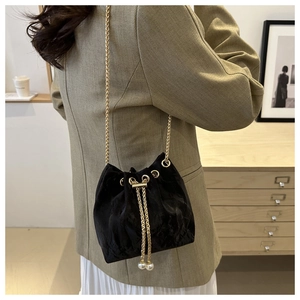 Detail of black velvet drawstring bucket bag with gold chain and large pearl accents