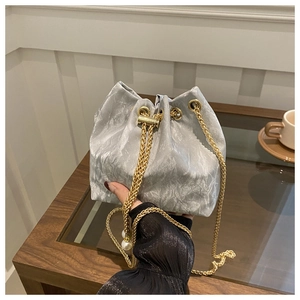 Detail of silver pleated bucket bag with gold chain strap and pearl pendant accent