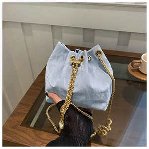 Detail of light blue bucket bag with gold chain strap, pearls, and pleated fabric texture