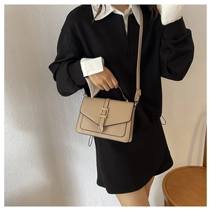 Khaki PU leather crossbody bag with gold buckle and V-shaped flap on model