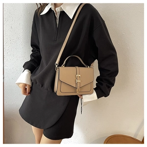 Detail of khaki leather crossbody bag featuring gold metal buckle and matching handle