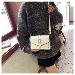 Close-up of cream envelope handbag with gold hardware and black edge detailing