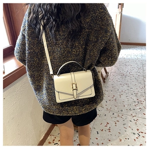 Rear view of a cream mini square bag with a top handle and adjustable strap on a model