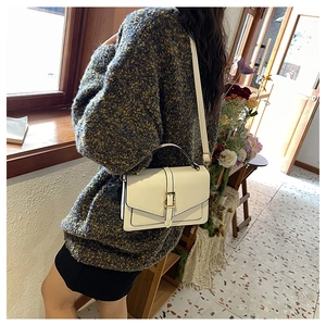 Close-up of cream vintage envelope crossbody bag with gold buckle and adjustable strap