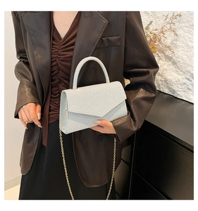Detail of silver rhinestone square bag with golden chain strap on a fashion model