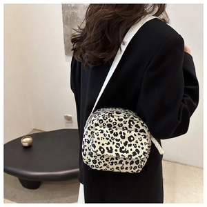 Detail shot of leopard print crossbody bag with front pocket on a model in a black suit