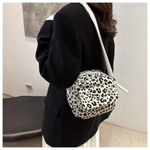 On-body view of a black and white leopard print canvas crossbody bag with white strap