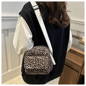 Leopard print crossbody bag with adjustable white strap shown on a female model