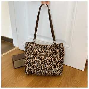 Detail of leopard print canvas tote bag with brown leather straps and metal hardware