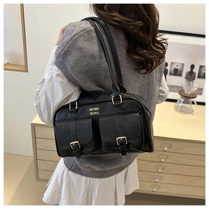 Detail showing the vintage black shoulder bag with dual gold buckle pockets and logo