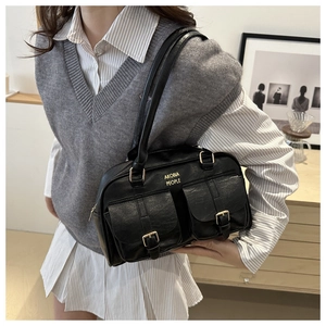 Detail of vintage black faux leather bag featuring double buckled pockets and gold logo