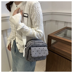 Detail of grey canvas crossbody bag with black polka dots and adjustable wide strap