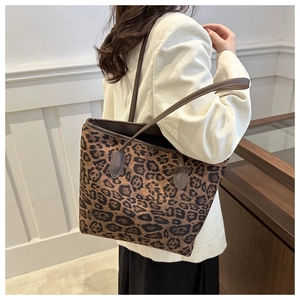 Close-up of leopard print tote bag with brown leather straps worn by a model in casual style