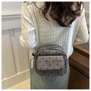 Détail du sac bandoulière en toile grise à pois noirs et tirette de zip blanche tressée