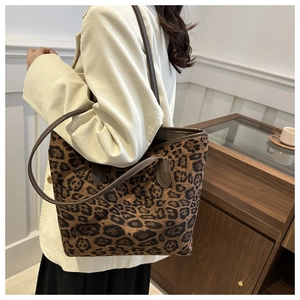 Detail shot of a large leopard print tote bag with brown leather straps on a model