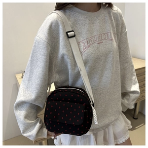 Mini canvas crossbody bag with red heart pattern and adjustable strap on model