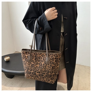 Grande borsa tote leopardata con manici marroni indossata da una modella in cappotto nero