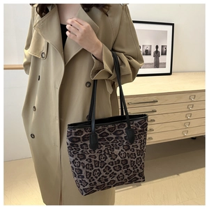Detail of leopard print tote bag styled with a classic trench coat in a cozy room