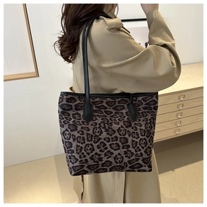 Detail of trendy leopard print tote bag with black leather straps and premium fabric texture