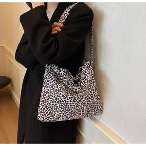 Detailed view of leopard print canvas tote bag with wide strap on a female model